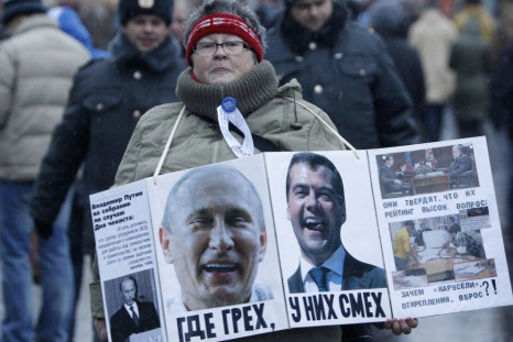 A woman carries a board displaying the portraits of Russia's President Dmitry Medvedev (R) and Prime Minister Vladimir Putin - December 10, 2011