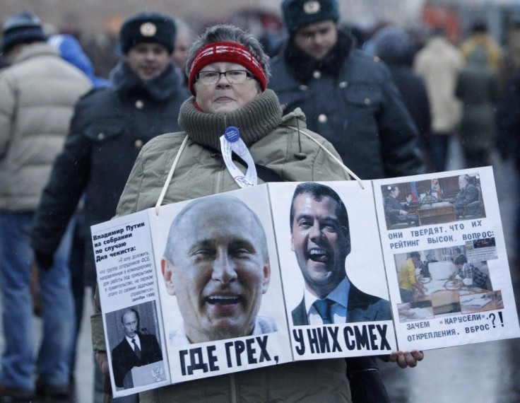 A woman carries a board displaying the portraits of Russia's President Dmitry Medvedev (R) and Prime Minister Vladimir Putin - December 10, 2011