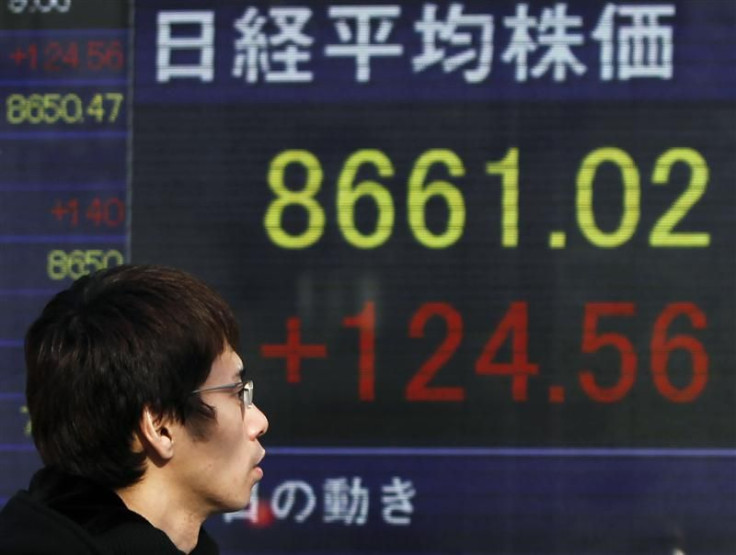 A man walks past an electronic board displaying Japan&#039;s Nikkei share average outside a brokerage in Tokyo