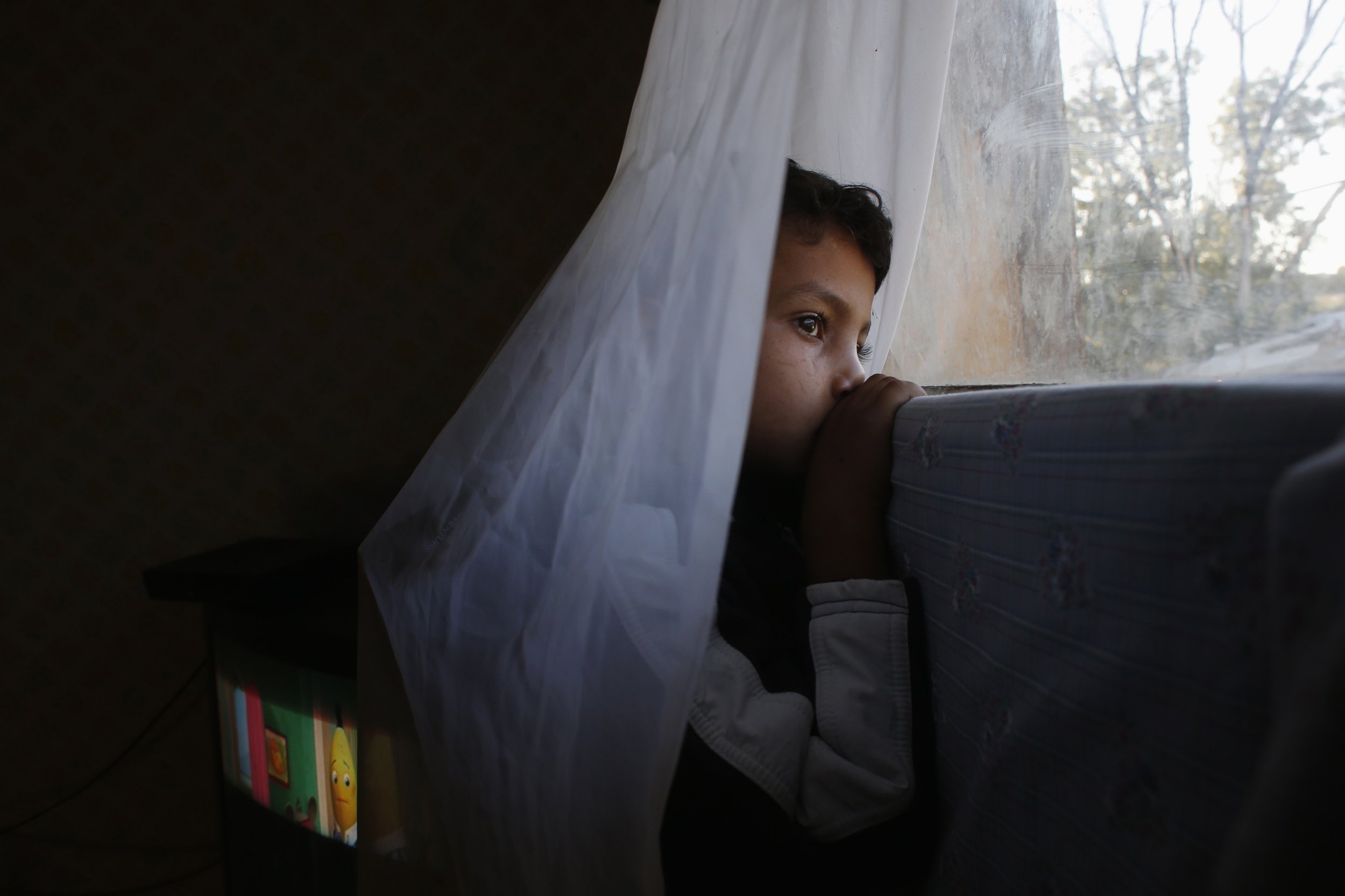 Six-year-old Abel watches from his window as an excavator demolishes a neighbors shack in Madrids El Gallinero slum.