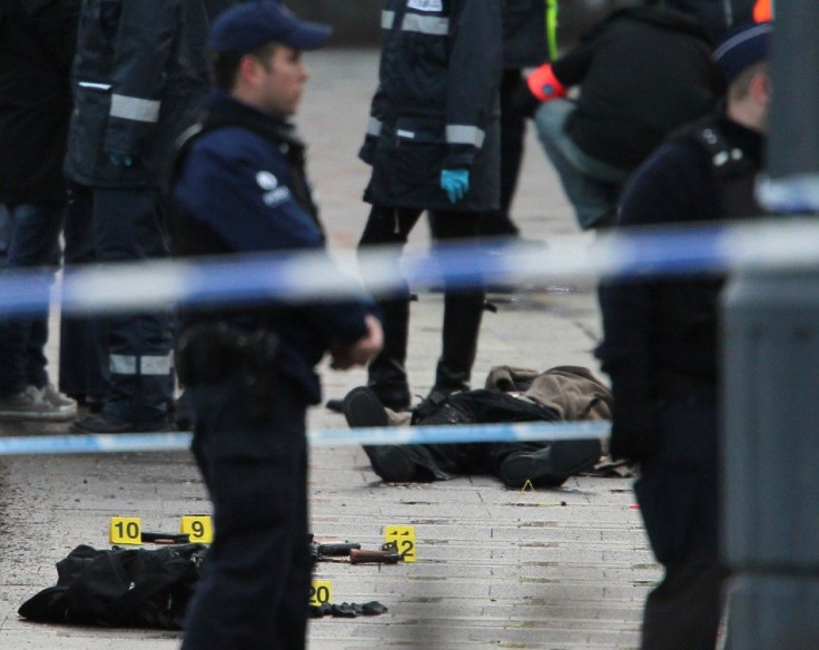 Police officers surround a dead body at the Place Saint Lambert square where a man threw explosives in the city center of the Belgian city of Liege