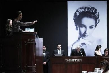 Christie&#039;s auctioneer Andrea Fiuczynski conducts an auction of Elizabeth Taylor&#039;s jewelry, clothing, art and memorabilia, near an image of the late actress at Christie&#039;s auction house in New York