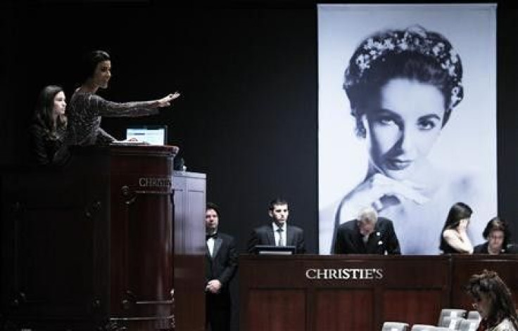 Christie&#039;s auctioneer Andrea Fiuczynski conducts an auction of Elizabeth Taylor&#039;s jewelry, clothing, art and memorabilia, near an image of the late actress at Christie&#039;s auction house in New York