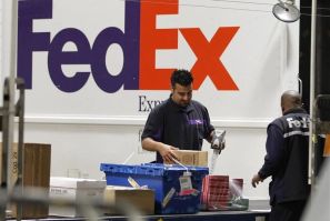 Handlers scan and affix a courier route label onto packages moving down the belt at the Marina Del Rey, California FedEx station