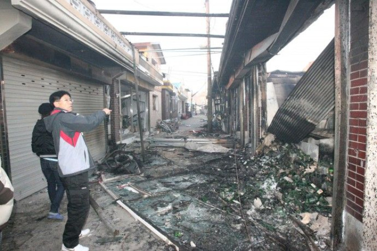 People stand beside houses, destroyed after they were hit by artillery shells fired by North Korea, on Yeonpyeong Island