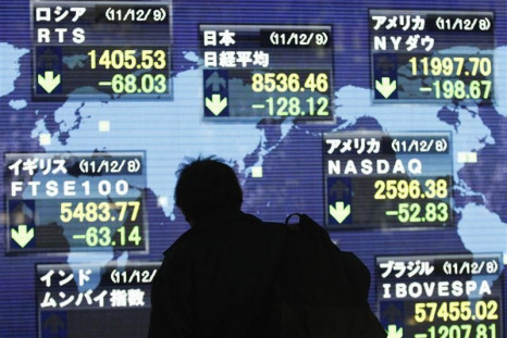 A man looks at an electronic board displaying a fall in major market indices
