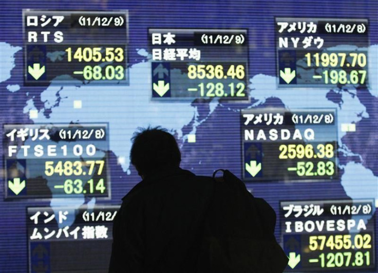 A man looks at an electronic board displaying a fall in major market indices