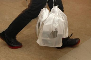 A man carries packs of Apple iPhone 4S, with each pack containing five sets, outside an Apple store in Hong Kong