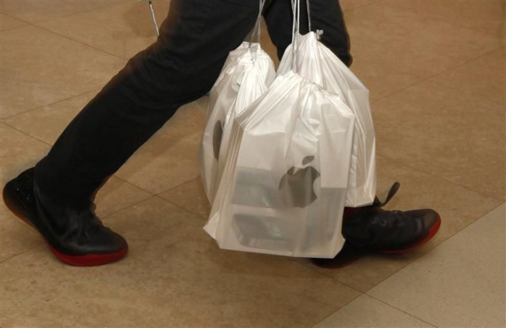 A man carries packs of Apple iPhone 4S, with each pack containing five sets, outside an Apple store in Hong Kong