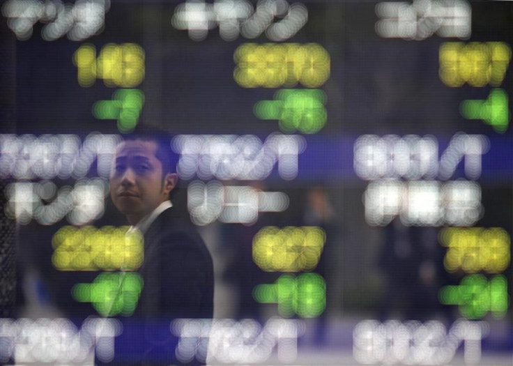 Man is reflected on an electronic board displaying stock prices outside a brokerage in Tokyo