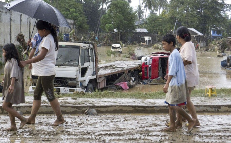 Residents walk past trucks swept away by flash floods due to heavy rains brought by Typhoon Washi, known locally as Sendong, in Iligan city, southern Philippines December 17, 2011.