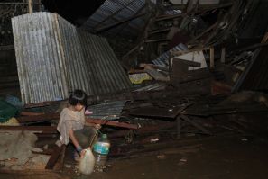 A boy fetches water from a broken pipe among destroyed houses along a road in a village hit by flashfloods caused by typhoon Washi in Cagayan de Oro, southern Philippines, December 17, 2011.