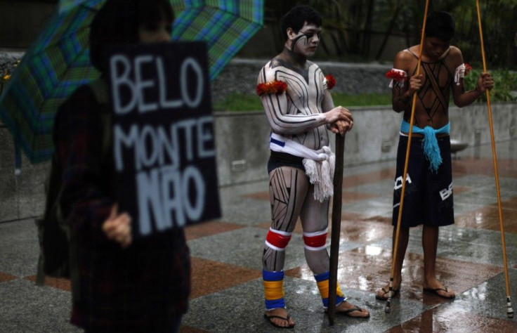 Brazilian indigenous men stand next to an environmental activist as he holds a banner that reads " Belo Monte, No" during a protest in Sao Paulo