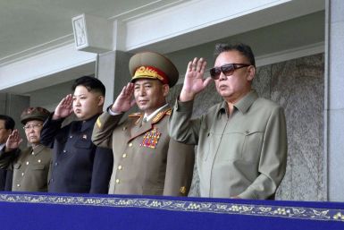 Kim Jong-il and his son Kim Jong-un salute as they watch soldiers attending a military parade