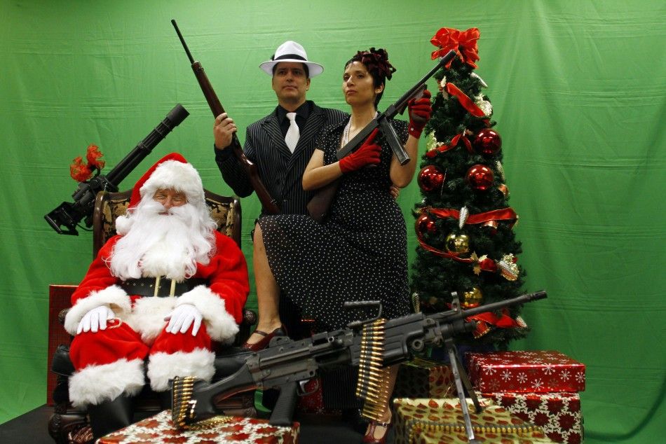 Todd Engle C and Mary Rose Engle R hold weapons as they pose for a photograph with a man dressed as Santa Claus at the Scottsdale Gun Club in Scottsdale, Arizona December 10, 2011.