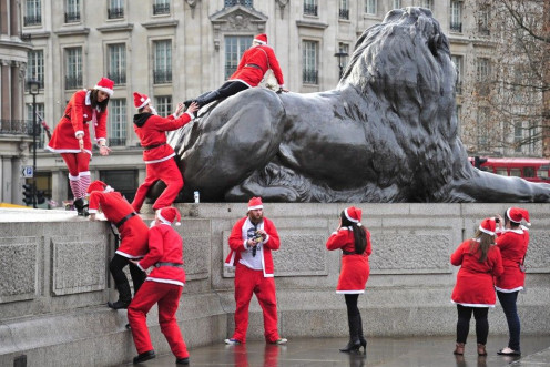 Revellers taking part in a &#039;Santa pub crawl&#039; dressed in seasonal costumes climb on statues in Trafalgar Square in London.