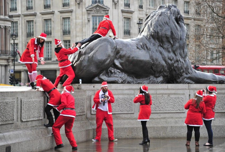Revellers taking part in a &#039;Santa pub crawl&#039; dressed in seasonal costumes climb on statues in Trafalgar Square in London.