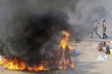 An Egyptian army soldier (R) arrests a protester near a burning tent during clashes at Tahrir Square in Cairo