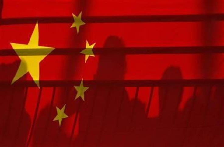 The shadows of spectators are seen through a Chinese national flag at the Beijing 2008 Olympic Games, August 12, 2008.