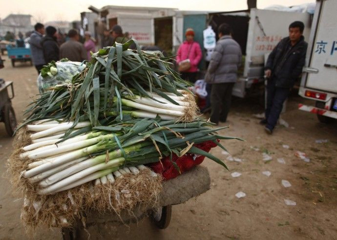 Vendors make deals with customers next to a pile of vegetables at Xinfadi open-air wholesale market in Beijing