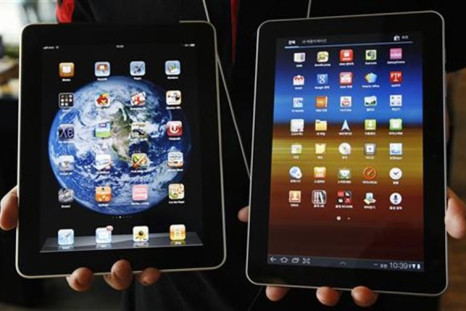 An employee of South Korean mobile carrier KT holds a Samsung Electronics&#039; Galaxy Tab 10.1 tablet and Apple Inc&#039;s iPad tablet as he poses in Seoul