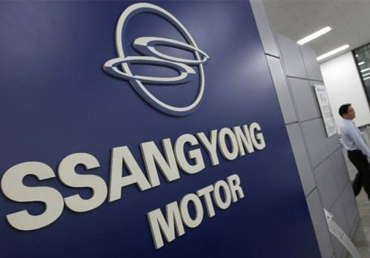 A salesperson from Ssangyong Motor walks past the company's logo at its branch shop in Seoul