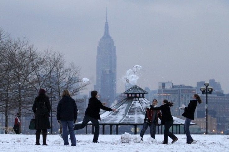 With New York's Empire State Building behind them, a group of friends play in the snow in a park along the Hudson River in Hoboken, New Jersey