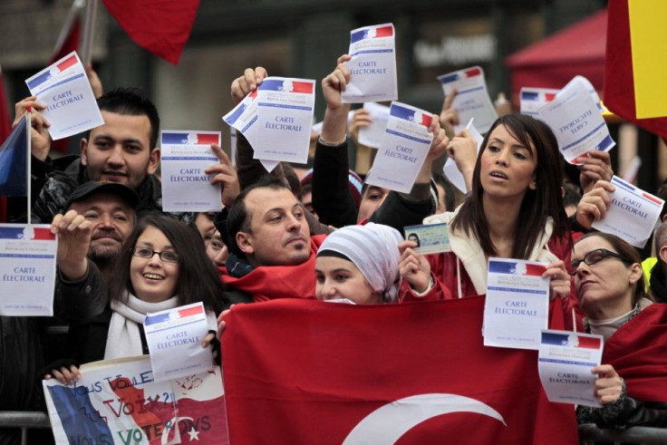 Franco-Turks protesters hold French electoral cards and a Turkish flag as they attend a demonstration next to the National Assembly in Paris