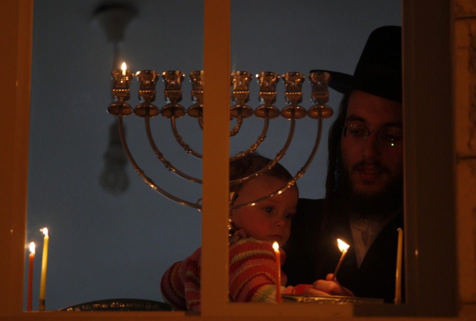 An Ultra-Orthodox Jewish man holds a child as he lights a candle for Hanukkah in Jerusalems Mea Shearim neighbourhood