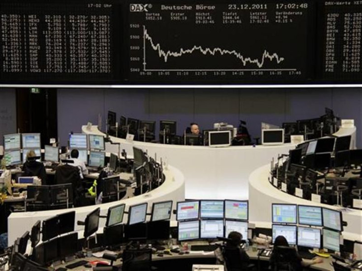 Traders are pictured at their desks in front of the DAX board at the Frankfurt stock exchange