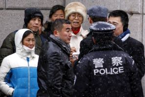 Supporters of Chinese rights activist Ni Yulan and her husband are pushed away by plain-clothes and uniformed police from the courthouse where activists are appearing on trial in Beijing