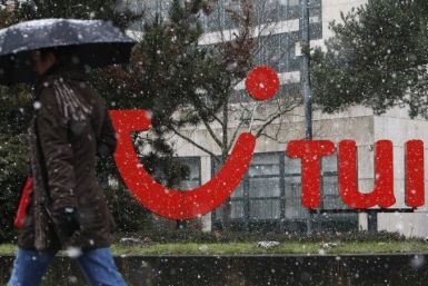 Woman with an umbrella walk past the logo of TUI AG outside the company's headquarters 