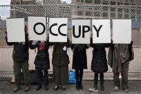 Protesters affiliated with the Occupy Wall Street movement stand with signs outside Duarte Square in New York