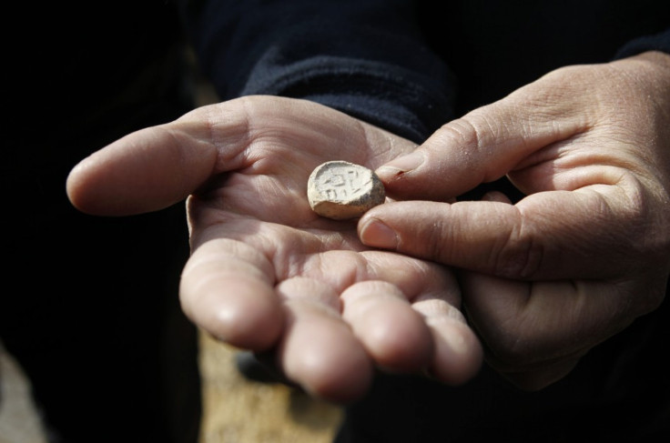 Israel Antiquities Authority (IAA) archaeologist Eli Shukron shows an ancient seal, at an archaeological site known as the City of David in Jerusalem