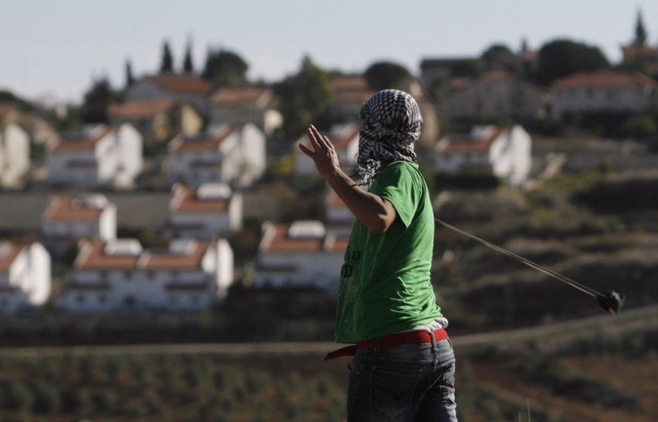 The West Bank Jewish settlement of Halamish is seen in the background as a Palestinian demonstrator uses a sling to throw a stone towards Israeli soldiers during clashes near Ramallah