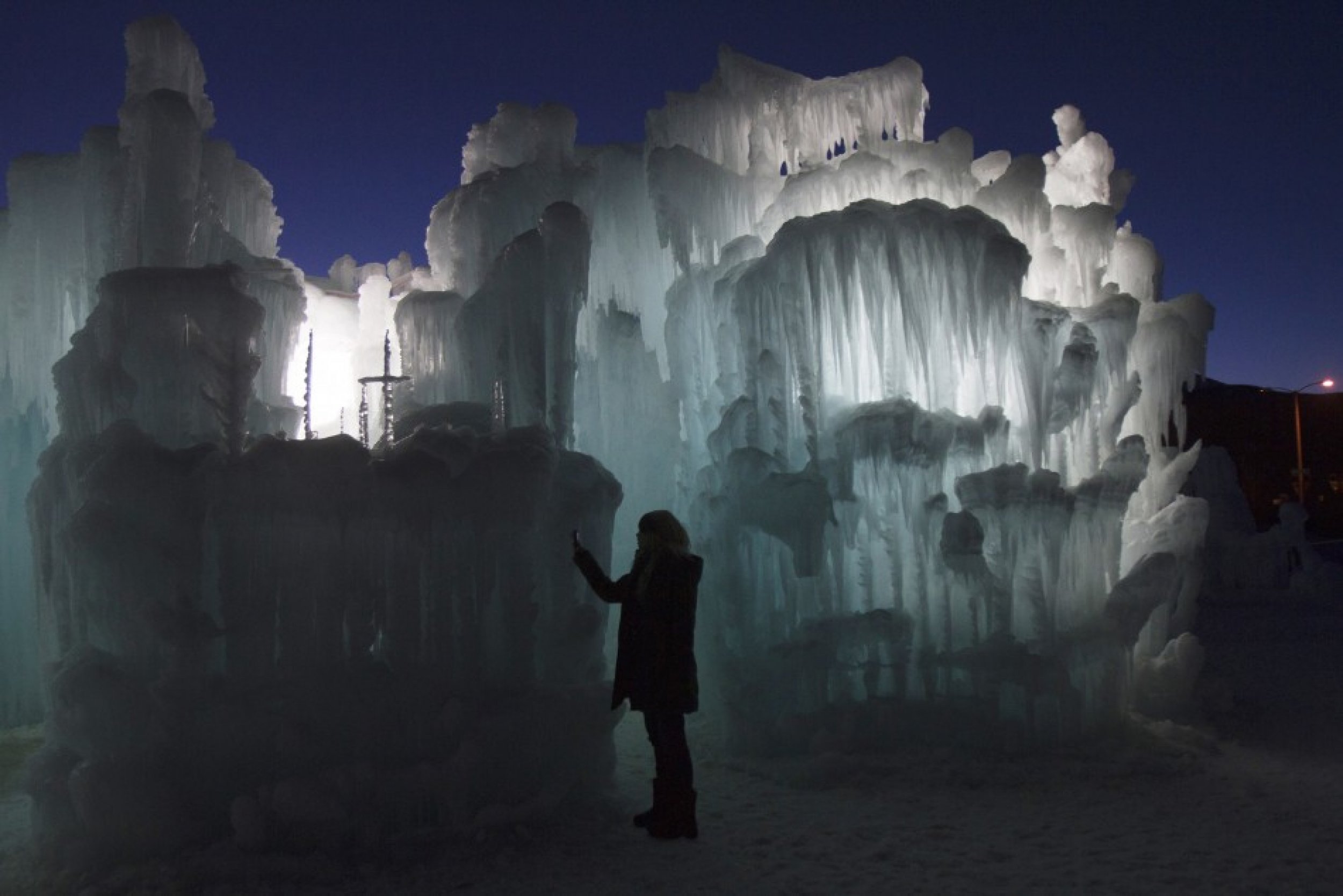 A tourist takes a photograph of ice formations at the Ice Castles at Silverthorne in Colorado