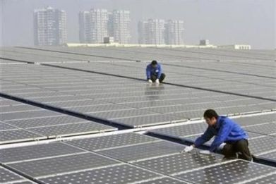 Technicians maintain solar panels on a roof at a solar power plant in Wuhan, Hubei province