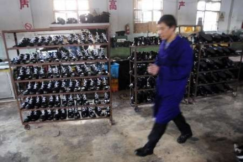 An employee walks in front of shelves with newly made shoes at a leather shoe factory in Hefei, Anhui province - file photo 