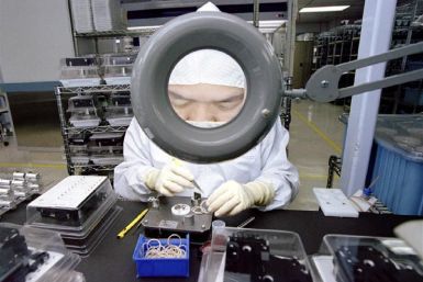 An employee of Seagate Technology is enlarged by a magnifying glass as she concentrates on assemblin..