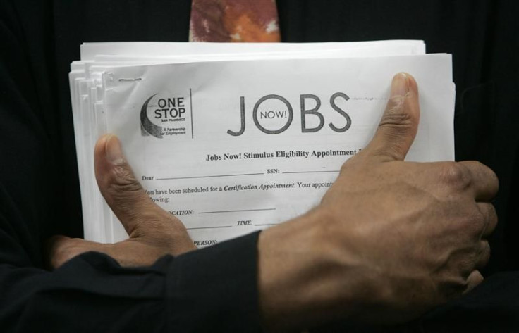 Man carrying a stack of job listings listens to a discussion at the One Stop employment center in San Francisco