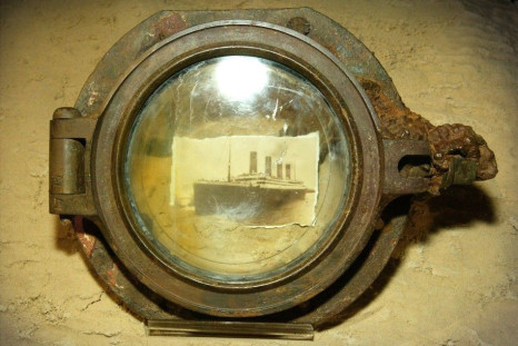 A photograph of the Titanic is seen through a porthole