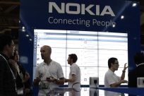 Staff members speak to trade visitors at the Nokia booth at the CommunicAsia expo in Singapore