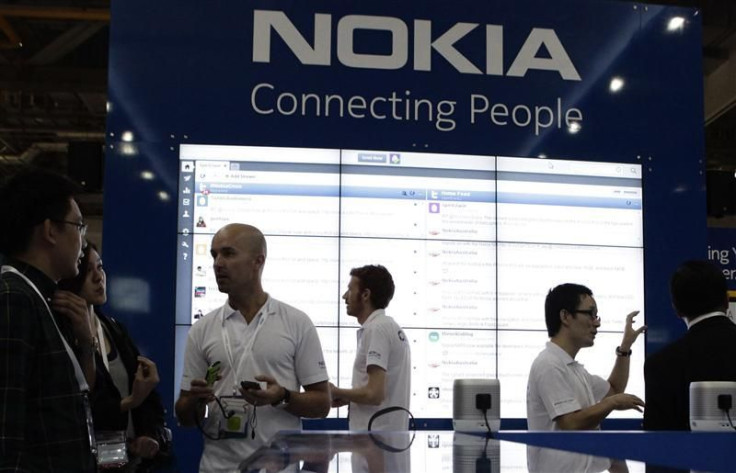 Staff members speak to trade visitors at the Nokia booth at the CommunicAsia expo in Singapore