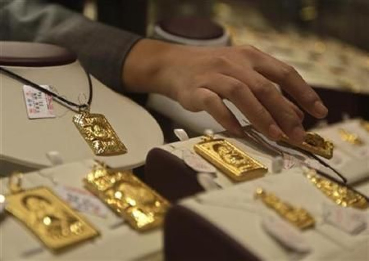 A sales assistant puts back a gold Buddha-shaped pendant after showing to a customer at Caibai Ornaments store in Beijing December 2, 2010.