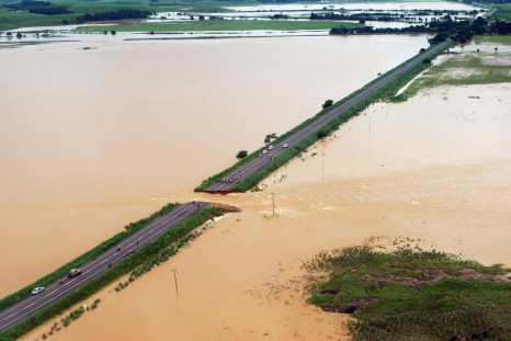 An aerial photograph shows a break in highway BR 356 that was washed away in Campos