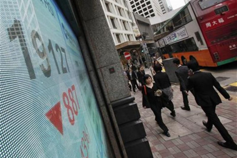 People walk past a panel displaying the blue-chip Hang Seng Index outside a branch of China Construction Bank in Hong Kong