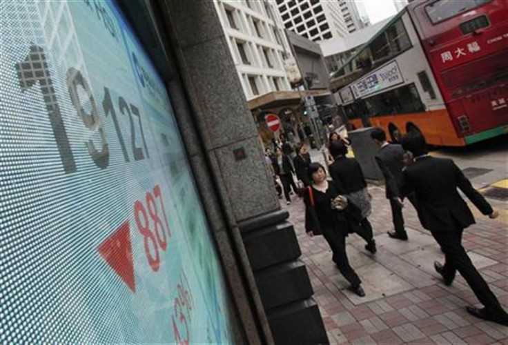 People walk past a panel displaying the blue-chip Hang Seng Index outside a branch of China Construction Bank in Hong Kong