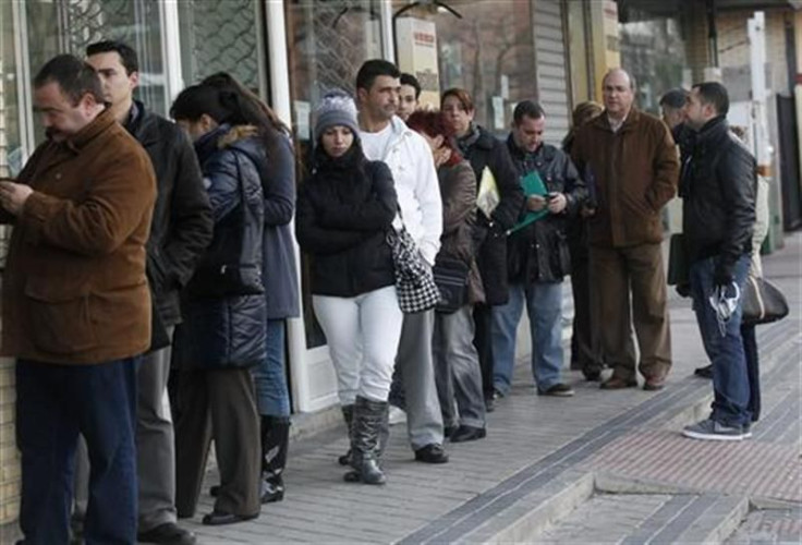 People wait in line for the opening of a government employment office in Madrid
