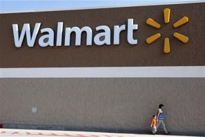 People walk past a Wal-Mart sign in Rogers, Arkansas