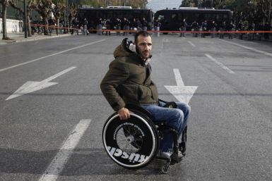 A protester with disabilities is seen in front of a police formation during a protest against austerity measures in Athens